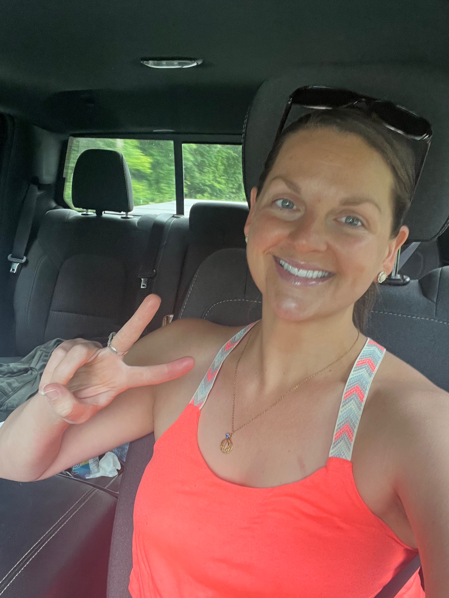 Sarah smiling in the car giving a peace sign